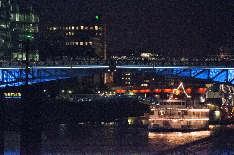 a ship on the water under a bridge at night