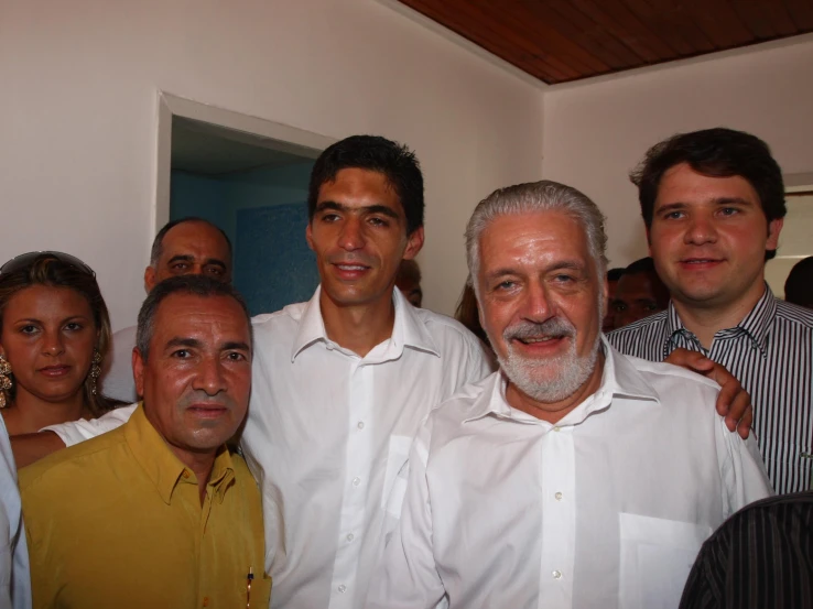 an old man standing between two men in white shirts