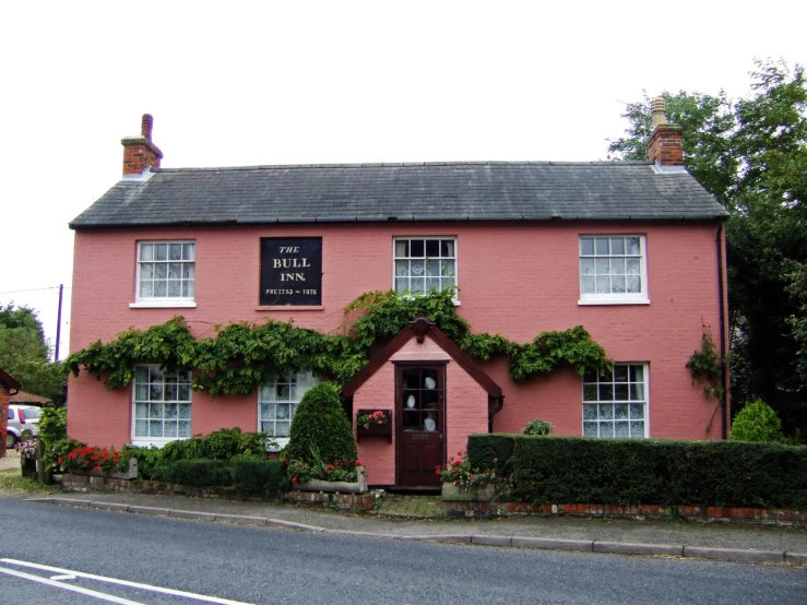 a pink building with vines on it next to a street