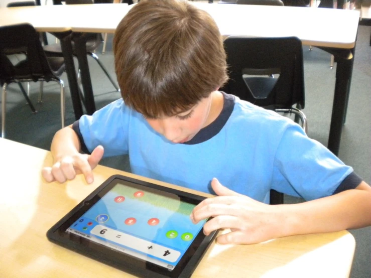 a boy in a blue shirt using an ipad