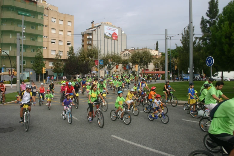 a large group of bicyclists cross a busy street