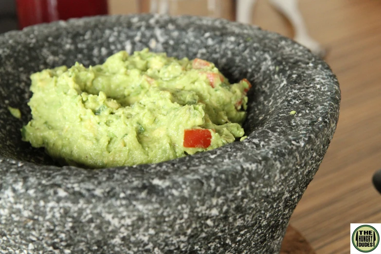 a bowl full of guacamole on top of a wooden table