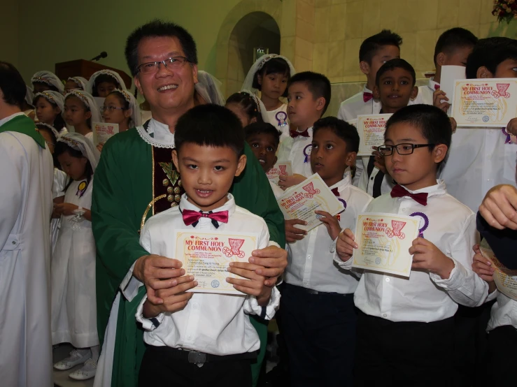 the school children are wearing all white and holding letters