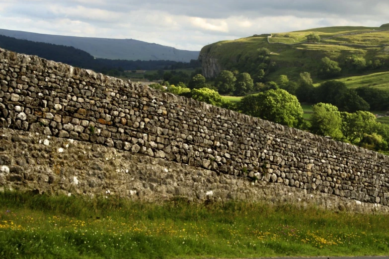 a large stone wall is in the middle of the grass