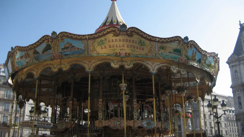a colorful carousel with large bells near a white building