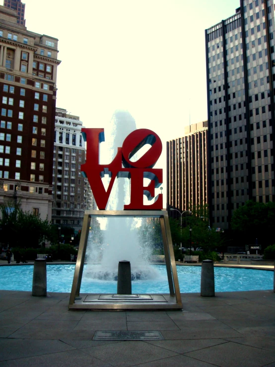 a love statue with a fountain of water in front of buildings