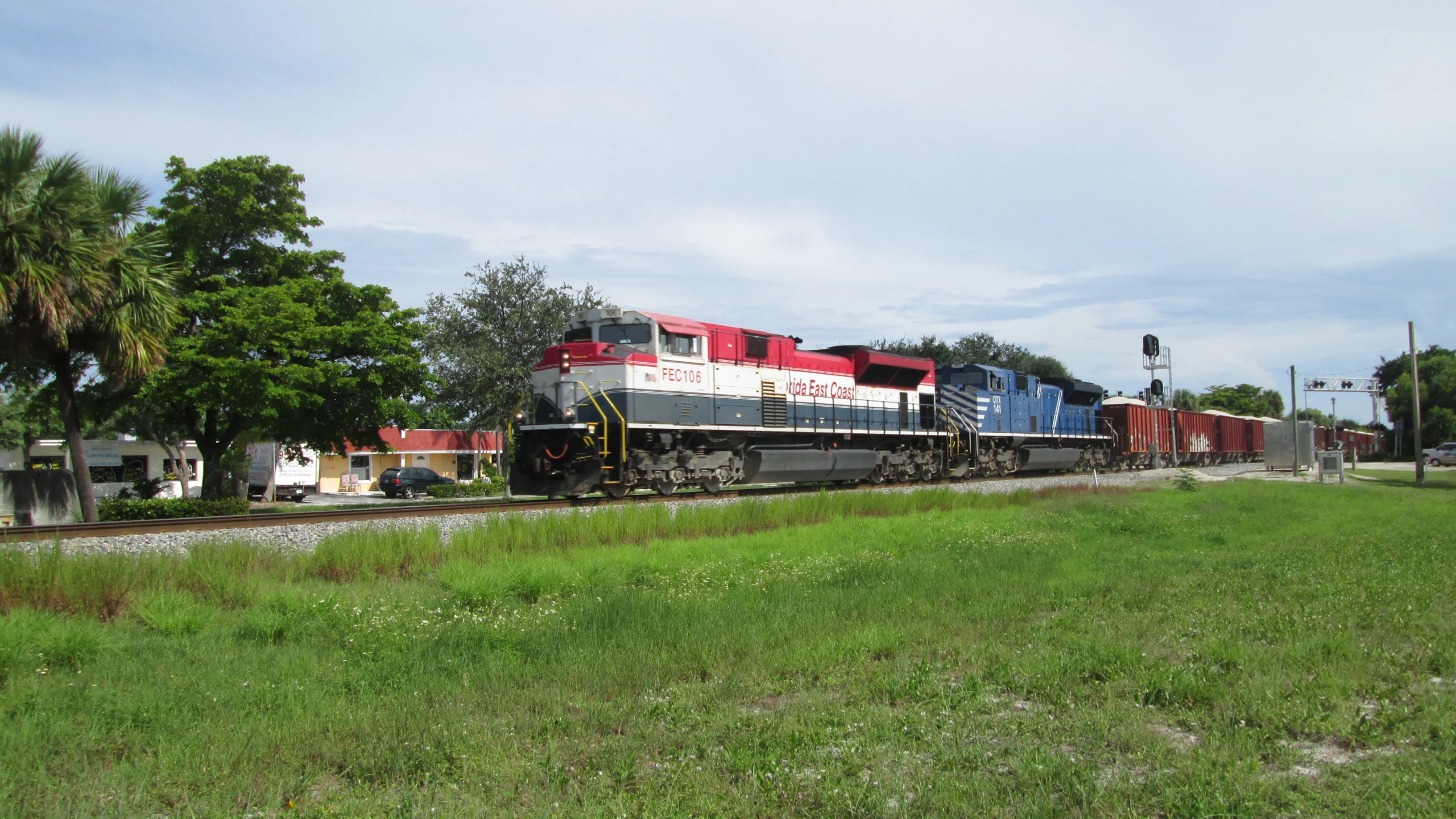 a red and black train traveling on a track next to trees