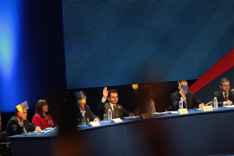 group of people sitting at a meeting table with hats on