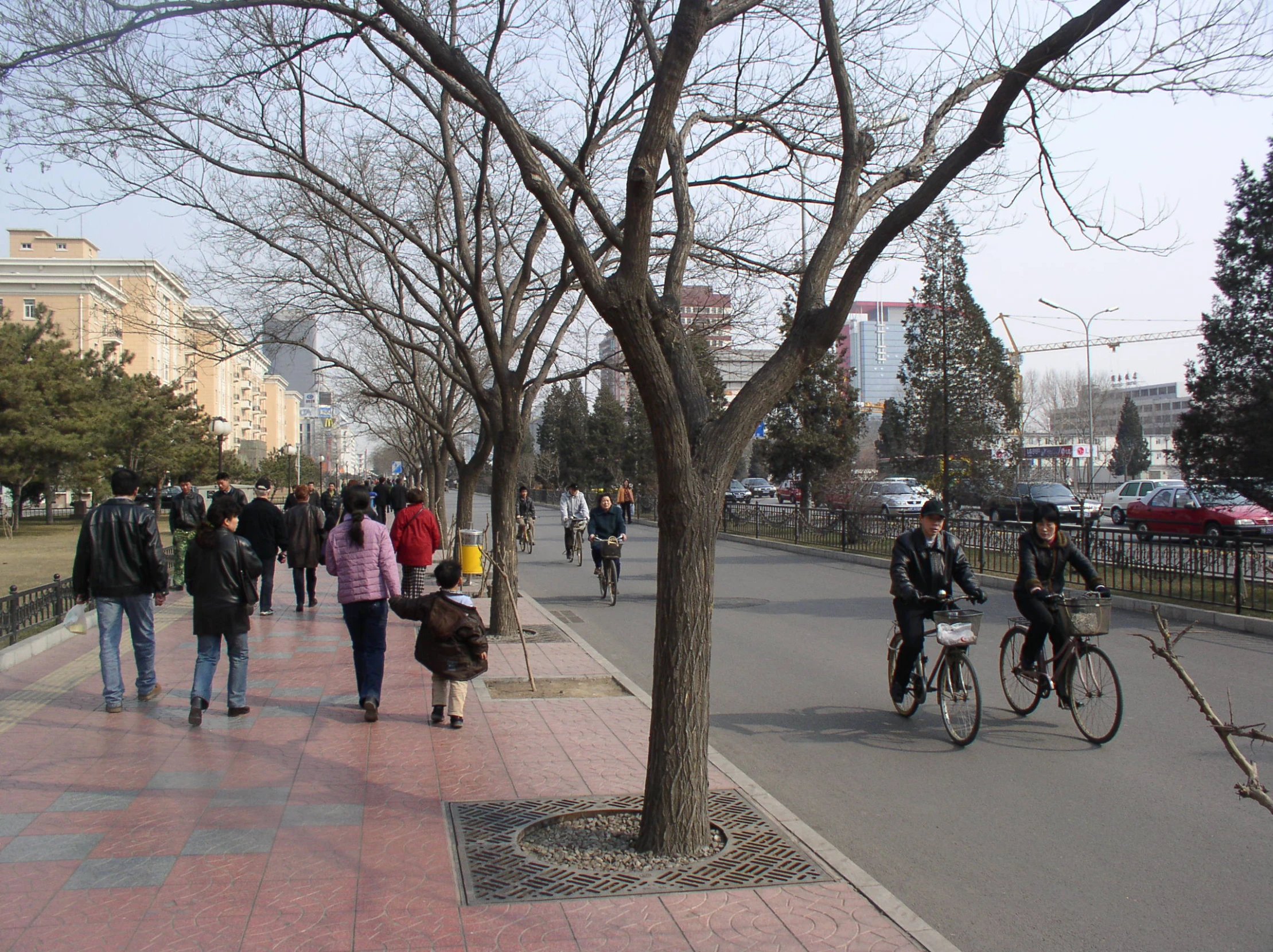 there is a lot of people that are walking and biking down the sidewalk