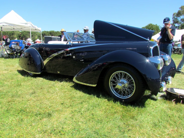 an old vintage car is parked on a green field