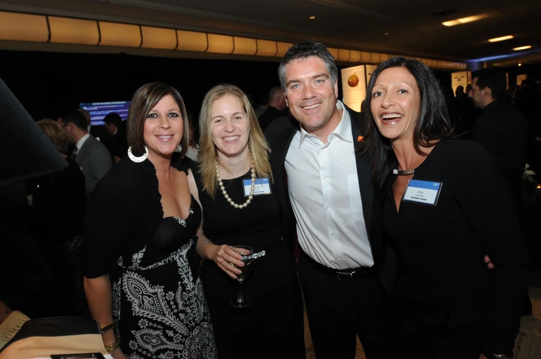 four women and one man smiling at an event