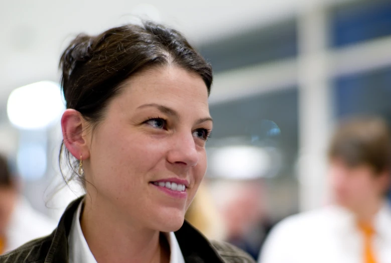 a young woman smiles for the camera in front of some other business people