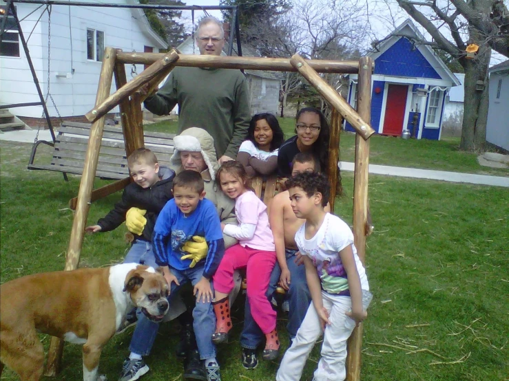 children and an adult posing for a picture in a yard with a dog