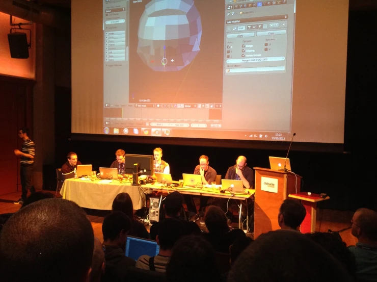 a group of people sitting at a table with a projector