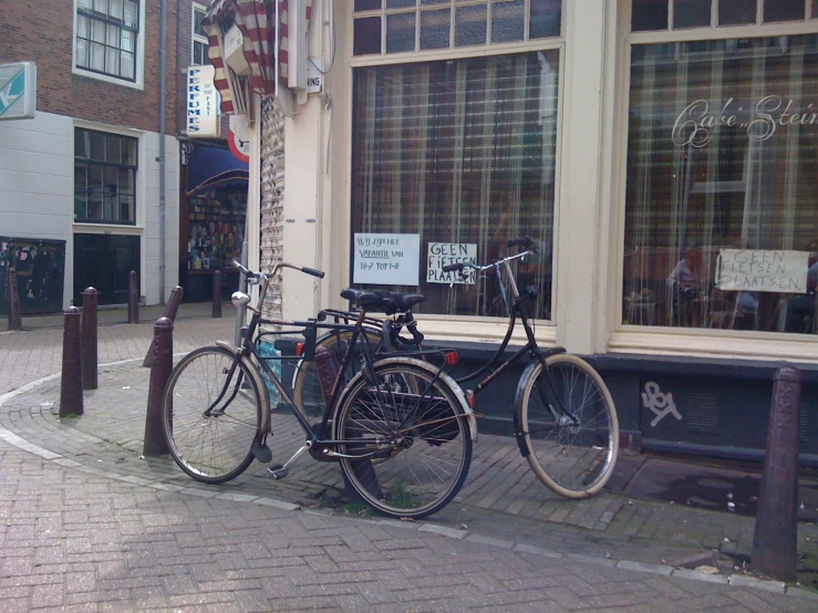 two bicycles are parked next to each other outside of a shop