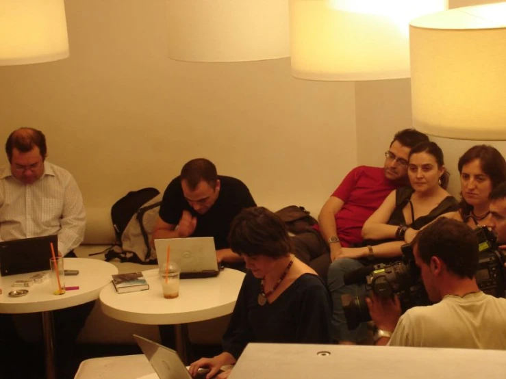 several people are sitting around a table working on laptops