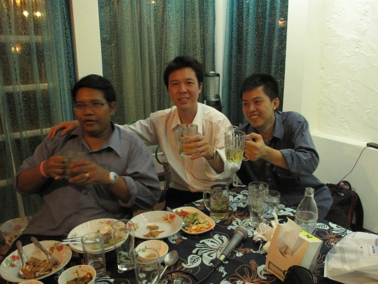 three men sitting at a dinner table drinking wine