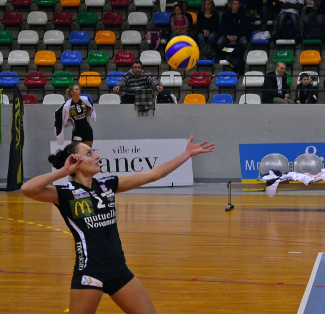 women playing volleyball, on a hardwood court