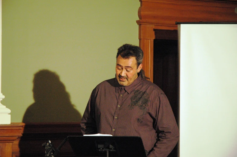 a man standing at a microphone with a music board