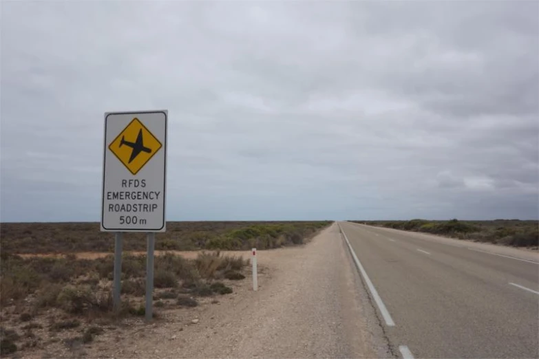 a warning sign for an airplane crossing on the side of the road