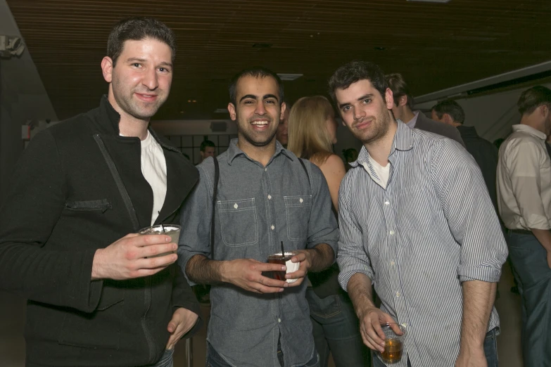 two men standing next to each other holding cups