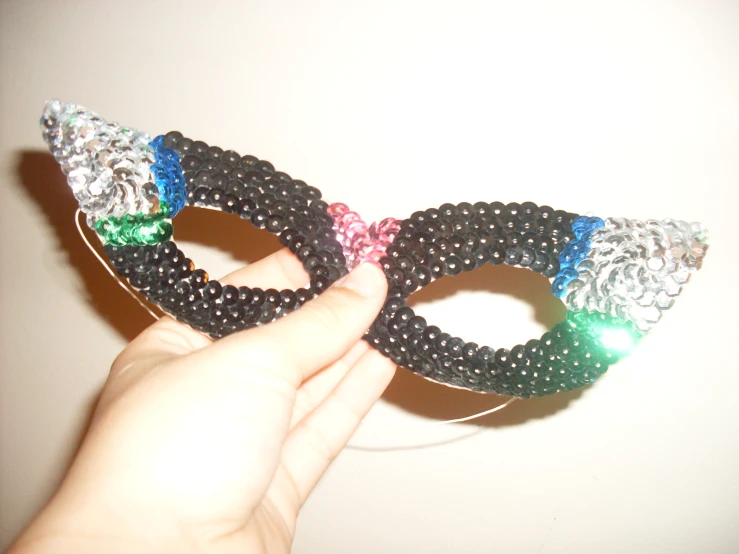pair of black and white beaded mask being held