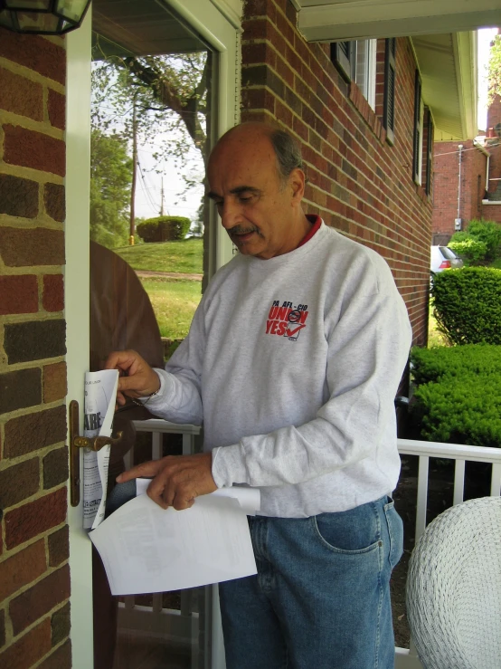 a man standing outside of his home holding papers