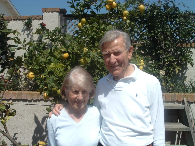 two people standing next to each other with oranges in the background