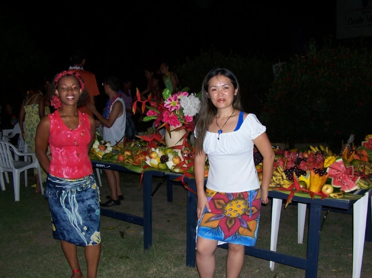 two women standing next to tables with flowers on them