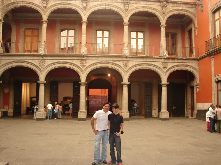 two guys standing in front of a building, one with his tongue out