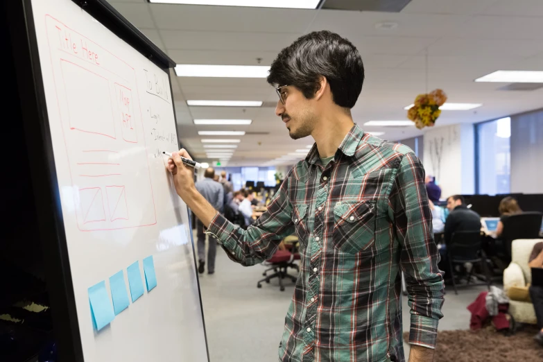 a person writing on a dry erase board