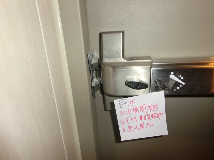 a door with a paper on the handle and a sign attached to it