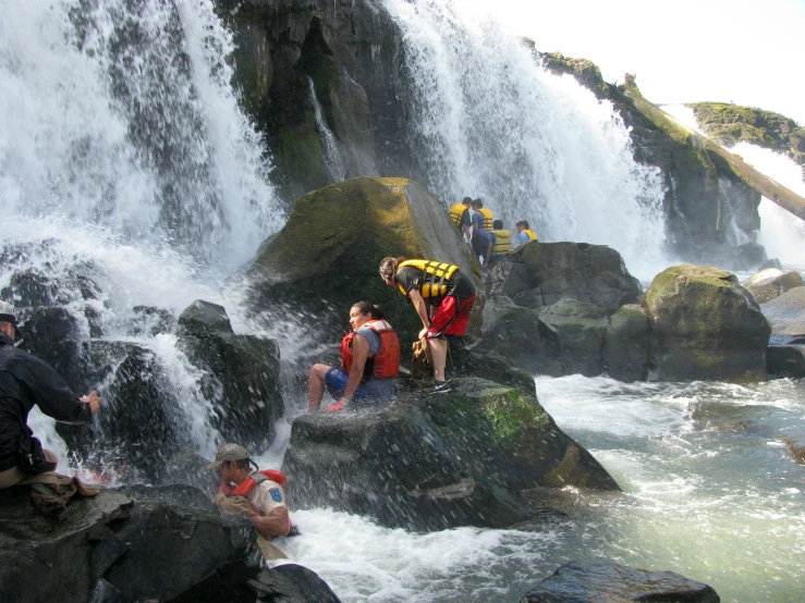 people with backpacks climbing up to a waterfall