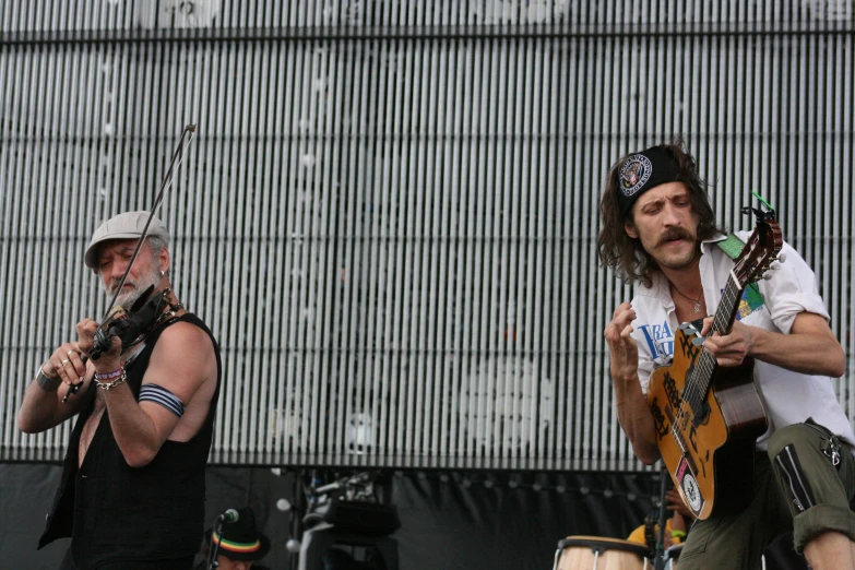 two men playing guitars at an outdoor music event