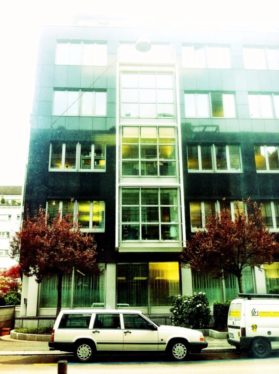 a car parked in front of a tall building with a bunch of windows