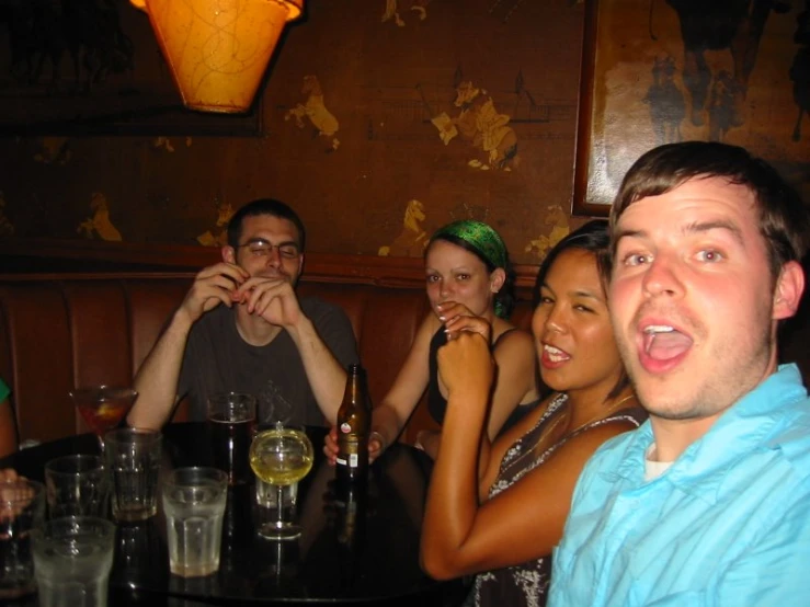 four people sitting at a table having wine and drinking