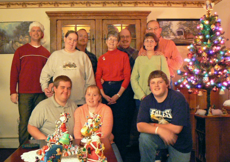 a group of people pose for a pograph with a christmas tree behind them