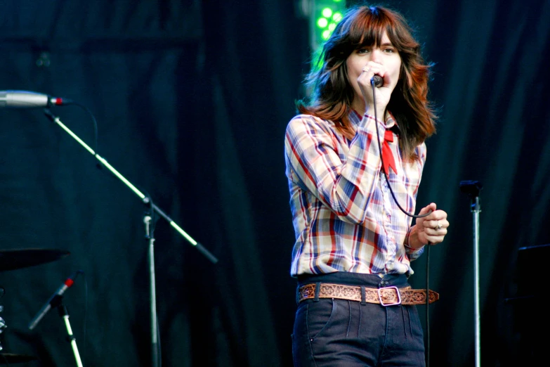 a girl with long hair is standing in front of microphones