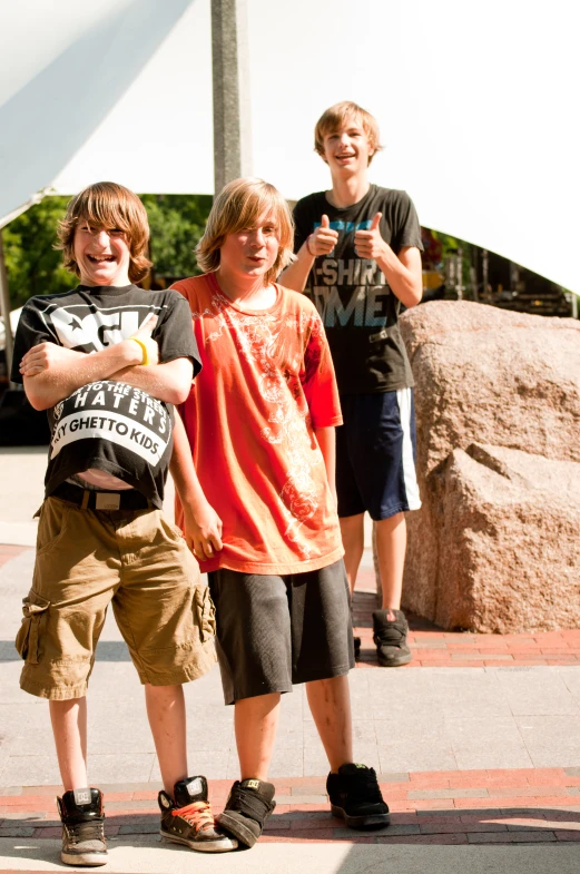 three boys are standing on the street smiling