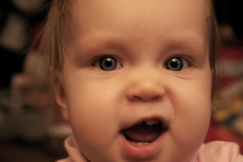 a little girl with blue eyes showing off her open mouth