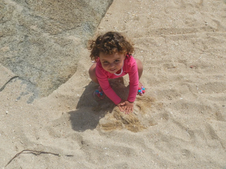 a  in pink shirt laying down in sand