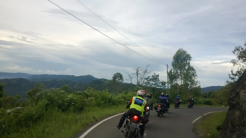 several motorcycle riders traveling down the country road