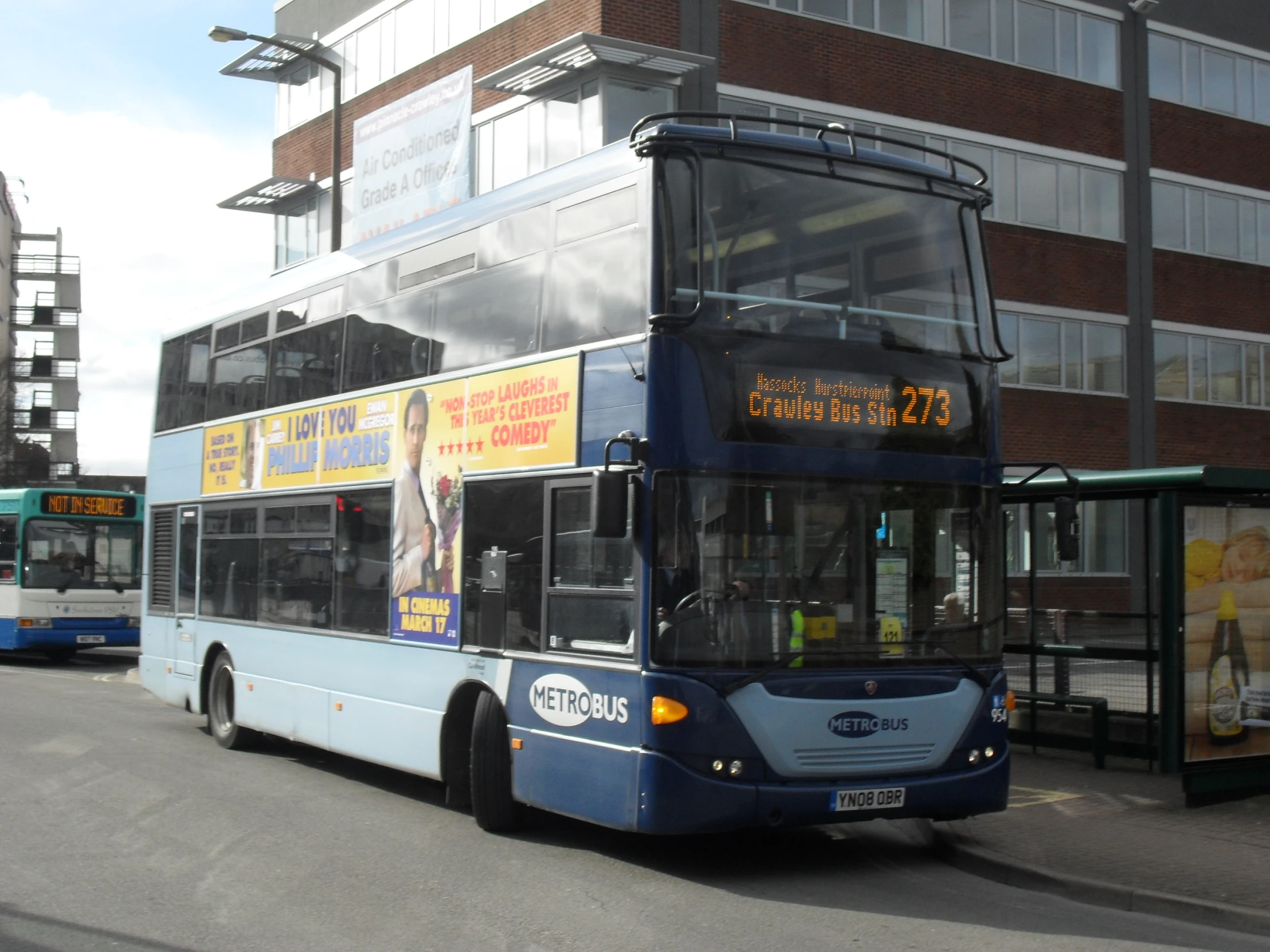 the blue double decker bus is on the street