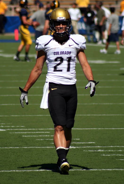 a man on a football field is wearing a uniform and gloves