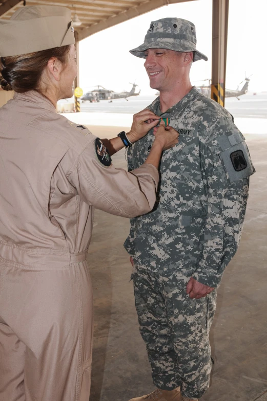 a woman in uniform getting the medal pinned to her husband