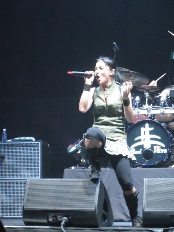 a woman wearing black sings into microphones at a concert