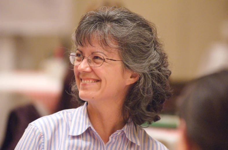 smiling middle aged woman in blue and white striped shirt