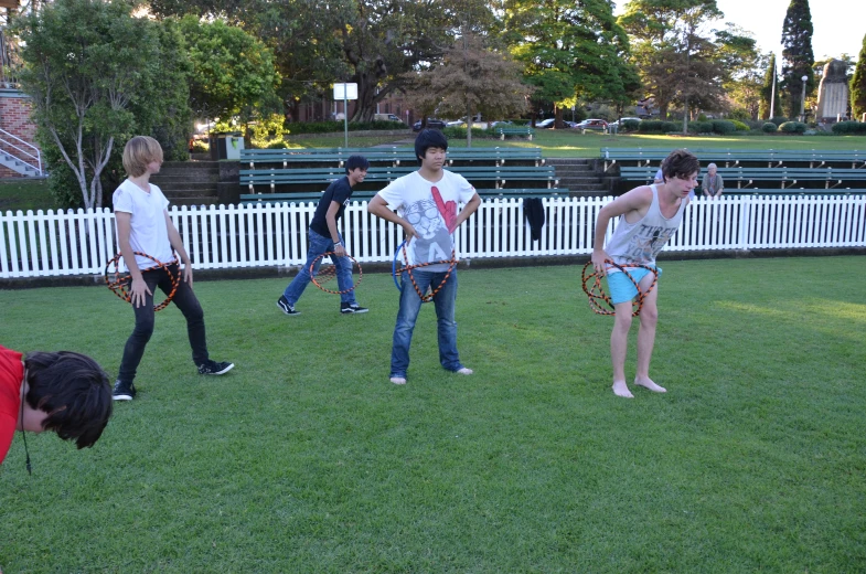 young men playing sports on a lawn with fences