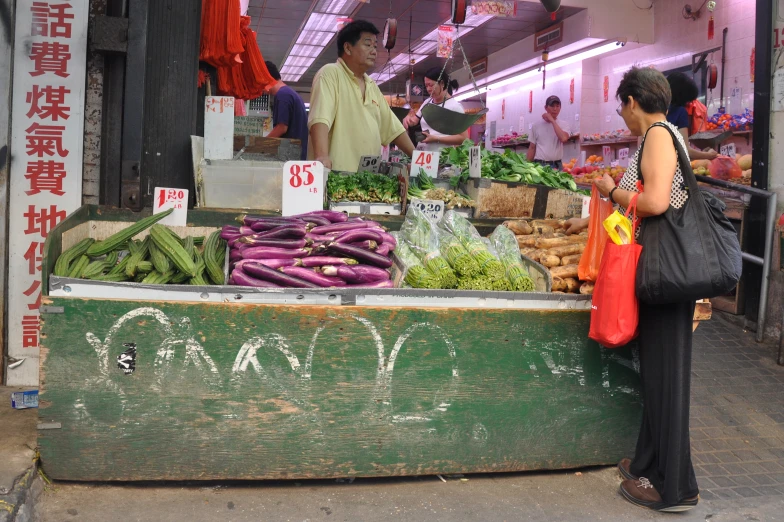 a market with people standing around it and looking at produce