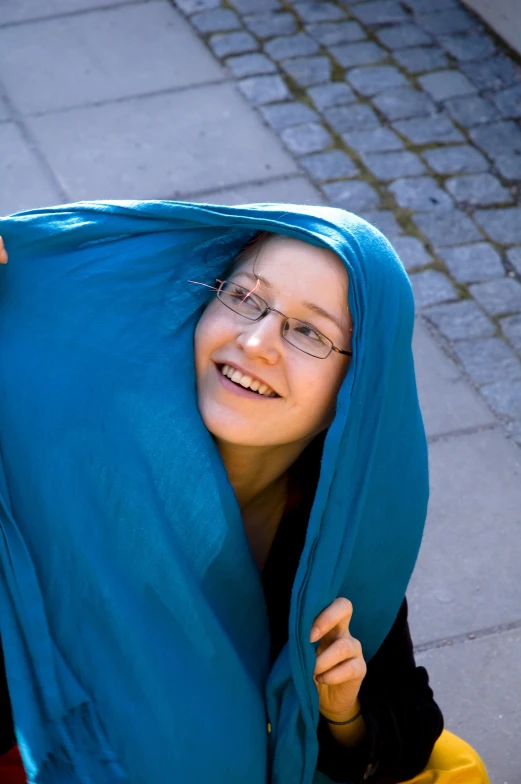 a woman wrapped in a blue fabric standing on a brick walkway